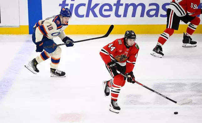 Chicago Blackhawks defenseman Wyatt Kaiser (44) moves the puck against Edmonton Oilers center Trent Frederic (10) during the second period of an NHL hockey game, Monday, Jan. 12, 2026, in Chicago. (AP Photo/Matt Marton)