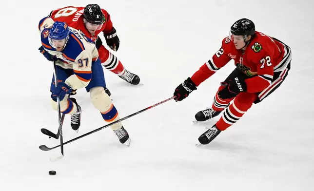 Edmonton Oilers center Connor McDavid (97) moves the puck against Chicago Blackhawks center Ryan Donato (8) and defenseman Alex Vlasic (72) during the second period of an NHL hockey game, Monday, Jan. 12, 2026, in Chicago. (AP Photo/Matt Marton)