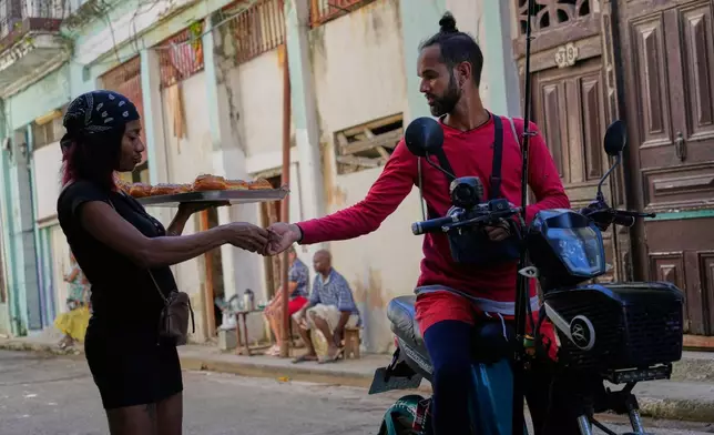 A motorist stops to buy a pastry from a vendor in Havana, Cuba, Thursday, Jan. 8, 2026. (AP Photo/Ramon Espinosa)
