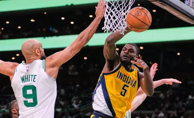 Indiana Pacers forward Jarace Walker (5) passes the ball while pressured by Boston Celtics guard Derrick White (9) during the first half of an NBA basketball game, Wednesday, Jan. 21, 2026, in Boston. (AP Photo/Charles Krupa)