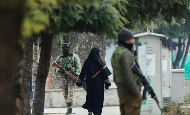 An Indian soldier and a policeman guard as a woman walks near the venue of India's Republic Day parade in Srinagar, Indian controlled Kashmir, Monday, Jan. 26, 2026. (AP Photo/Mukhtar Khan)