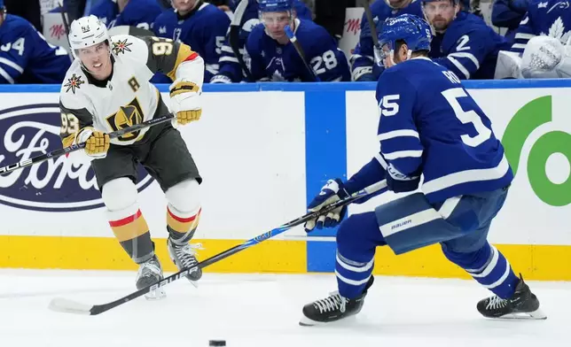 Vegas Golden Knights' Mitch Marner (93) and Toronto Maple Leafs' Nicolas Roy, right, battle for the puck during first-period NHL hockey game action in Toronto, Friday, Jan. 23, 2026. (Nathan Denette/The Canadian Press via AP)