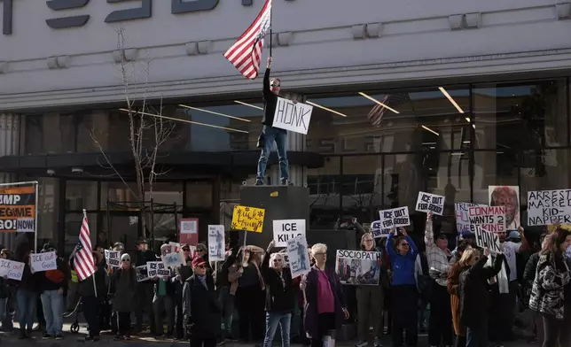 People protest outside the Tesla showroom against immigration enforcement and U.S. oil interests, in San Francisco, Saturday, Jan. 10, 2026. (Yalonda M. James/San Francisco Chronicle via AP)