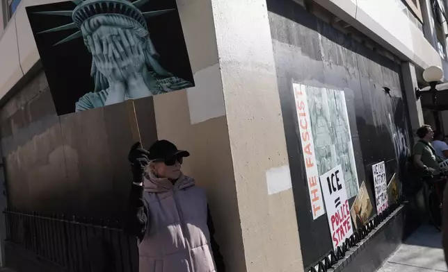 A woman holds a sign depicting an image of a weeping statue of liberty during a protest outside the Tesla showroom against immigration enforcement and U.S. oil interests, in San Francisco, Saturday, Jan. 10, 2026. (Yalonda M. James/San Francisco Chronicle via AP)