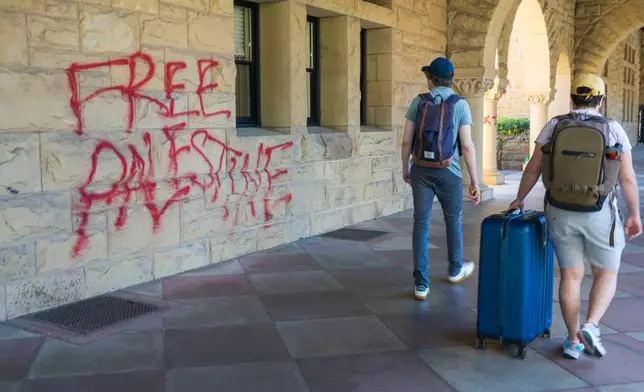 FILE - Students walk by graffiti near university president Richard Saller's office at Stanford University in Palo Alto, Calif., June 5, 2024. (AP Photo/Nic Coury, File)