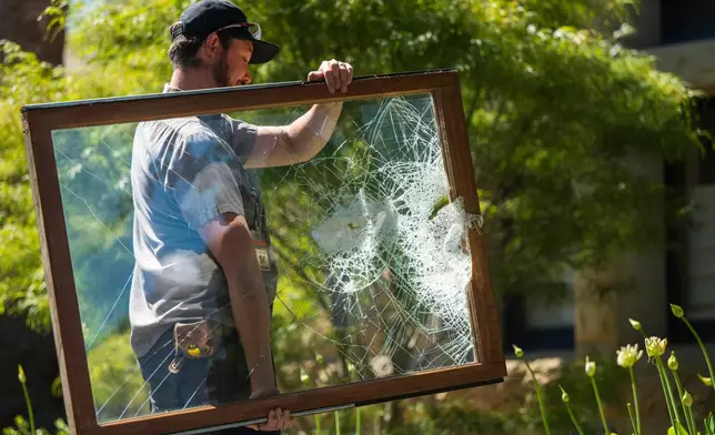 FILE - A campus maintenance worker carries a broken window from the office of the president at Stanford University in Palo Alto, Calif., June 5, 2024. (AP Photo/Nic Coury, File)
