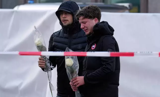 People bring flowers to the sealed off Le Constellation bar in Crans-Montana, Swiss Alps, Switzerland, Saturday, Jan. 3, 2026, where a devastating fire left dead and injured during the New Year's celebrations. (AP Photo/Baz Ratner)