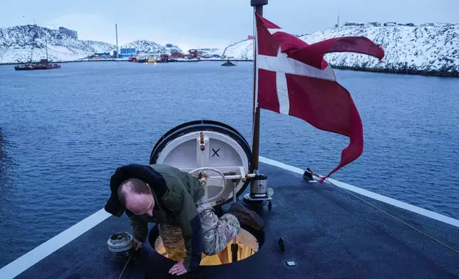 A Danish serviceman climbs out of a hatch on the bow of the military vessel HDMS Knud Rasmussen of the Royal Danish Navy docked in Nuuk, Greenland, on Saturday, Jan. 17, 2026. (AP Photo/Evgeniy Maloletka)