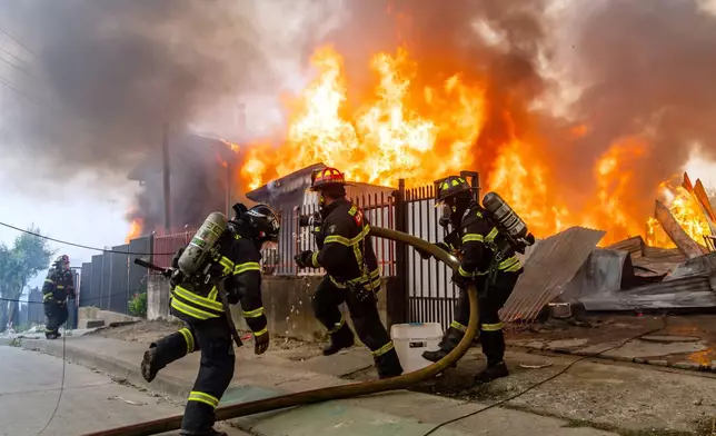 Firefighters battle a blaze at a house as wildfires burn in Lirquen, Chile, Sunday, Jan. 18, 2026. (AP Photo/Javier Torres)