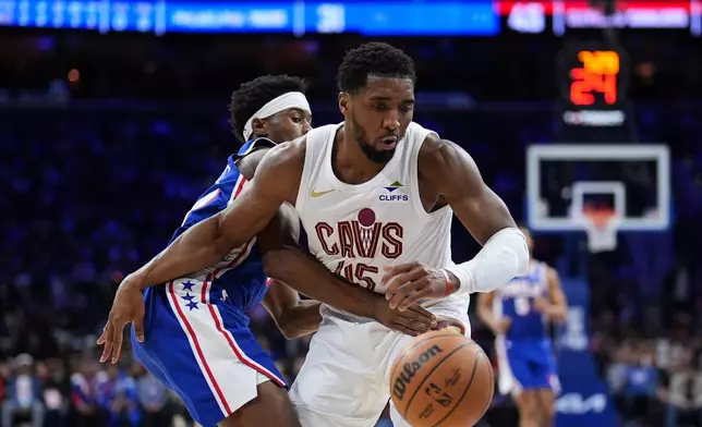 Cleveland Cavaliers' Donovan Mitchell, right, battles for the ball against Philadelphia 76ers' Vj Edgecombe during the first half of an NBA basketball game Wednesday, Jan. 14, 2026, in Philadelphia. (AP Photo/Matt Slocum)