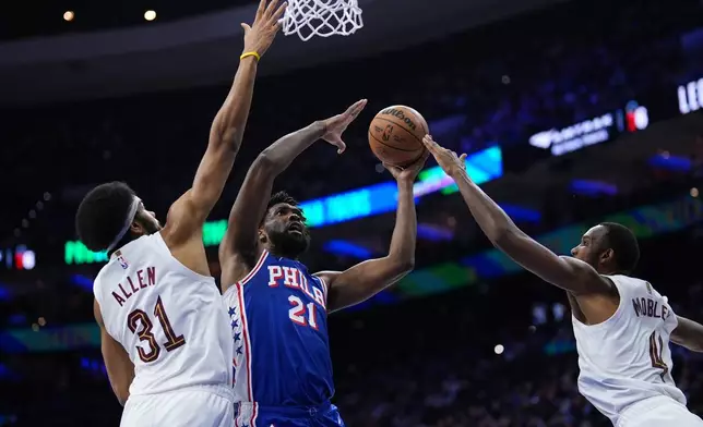 Philadelphia 76ers' Joel Embiid, center, goes up for a shot between Cleveland Cavaliers' Jarrett Allen, left, and Evan Mobley during the first half of an NBA basketball game Wednesday, Jan. 14, 2026, in Philadelphia. (AP Photo/Matt Slocum)