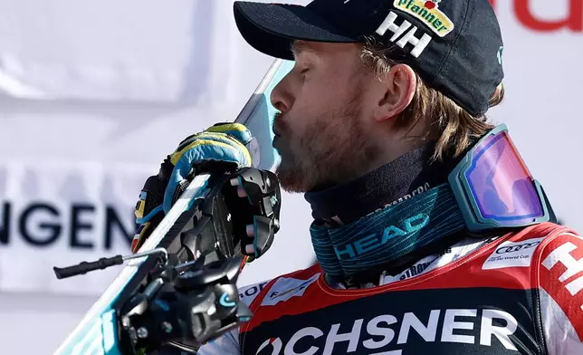 Norway's Atle Lie McGrath kisses his skis as he celebrates on the podium after winning an alpine ski, men's World Cup slalom, in Wengen, Switzerland, Sunday, Jan. 18, 2026. (AP Photo/Gabriele Facciotti)