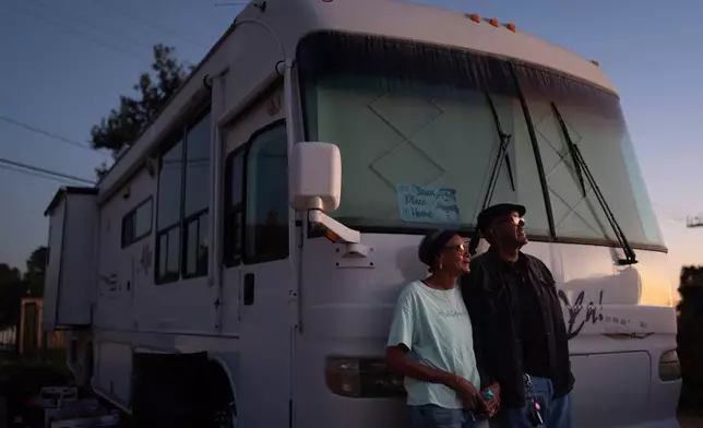 Ellaird Bailey and his wife, Charlotte, who lost their home in the Eaton Fire, stand for a photo in front of their RV, which is parked on the property where their house once stood, Dec. 11, 2025, in Altadena, Calif. (AP Photo/Jae C. Hong)
