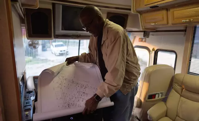 Ellaird Bailey, who lives in an RV on the property where his home was destroyed in the Eaton Fire, looks at building plans, Dec. 12, 2025, in Altadena, Calif. (AP Photo/Jae C. Hong)
