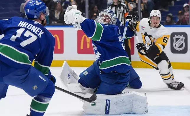 Vancouver Canucks goalie Kevin Lankinen, cener, fails to catch the puck as teammate Filip Hronek (17) and Pittsburgh Penguins' Rickard Rakell (67) watch during first-period NHL hockey game action in Vancouver, British Columbia, Sunday, Jan. 25, 2026. (Darryl Dyck/The Canadian Press via AP)