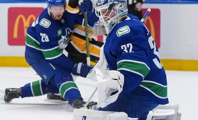 Vancouver Canucks goalie Kevin Lankinen (32) watches the puck after making a save during first-period NHL hockey game action against the Pittsburgh Penguins in Vancouver, British Columbia, Sunday, Jan. 25, 2026. (Darryl Dyck/The Canadian Press via AP)
