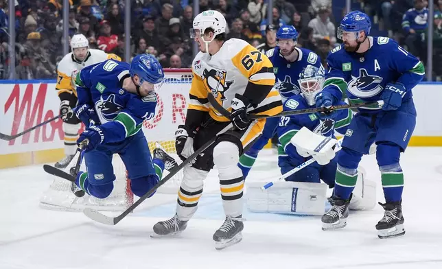 Vancouver Canucks' Elias Pettersson (40) falls in front of Pittsburgh Penguins' Rickard Rakell (67) as Canucks' Filip Hronek (17) and goalie Kevin Lankinen (32) watch during second-period NHL hockey game action in Vancouver, British Columbia, Sunday, Jan. 25, 2026. (Darryl Dyck/The Canadian Press via AP)