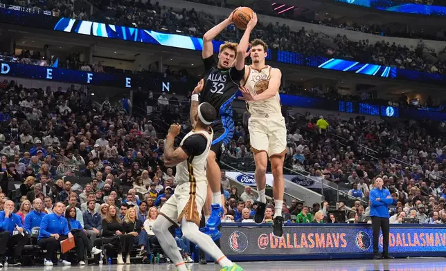 Dallas Mavericks forward Cooper Flagg (32) comes down with a rebound against Golden State Warriors' Gary Payton II, left, and Quinten Post, right, in the first half of an NBA basketball game in Dallas, Thursday, Jan. 22, 2026. (AP Photo/Tony Gutierrez)