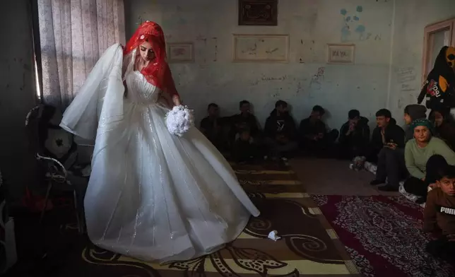 A Syrian bride displaced from the town of Al-Tabqa in northern Syria attends her wedding ceremony inside a classroom at a school being used as a shelter following clashes between Syrian government forces and the Kurdish-led Syrian Democratic Forces in Qamishli, northeastern Syria, Monday, Jan. 26, 2026. (AP Photo/Baderkhan Ahmad)