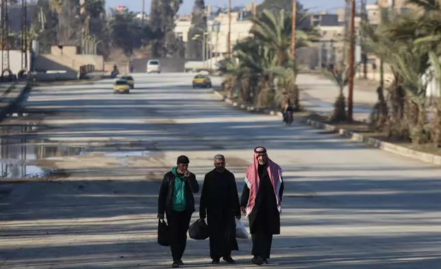 Men walk along a street in Hassakeh, northeastern Syria, Sunday, Jan. 25, 2026, as the city saw a gradual return to daily life following the announcement of a 15-day ceasefire between the Syrian government and the Kurdish-led Syrian Democratic Forces. (AP Photo/Baderkhan Ahmad)