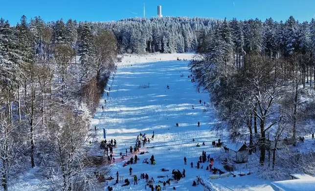 People ski and sled on a hill with the last call ski lift in Oberreifenberg in the Taunus region near Frankfurt, Germany, Sunday, Jan. 11, 2026. (AP Photo/Michael Probst)