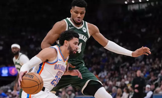Oklahoma City Thunder's Ajay Mitchell tries to get past Milwaukee Bucks' Giannis Antetokounmpo during the first half of an NBA basketball game Wednesday, Jan. 21, 2026, in Milwaukee. (AP Photo/Morry Gash)