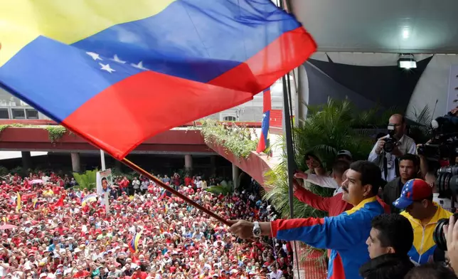 FILE - Venezuela's acting President Nicolas Maduro waves a national flag over supporters after registering his candidacy for president to replace late President Hugo Chavez at the national electoral council in Caracas, Venezuela, March 11, 2013. (AP Photo/Ariana Cubillos, File)