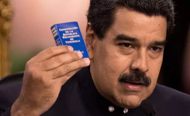 FILE - Venezuela's President Nicolas Maduro holds a copy of the constitution, as he speaks during a news conference in Caracas, Venezuela, Aug. 22, 2017. (AP Photo/Ariana Cubillos, File)
