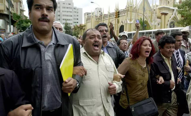 FILE - Pro-government lawmakers from left: Nicolas Maduro, Francisco Solorzano and Cilia Flores, surrounded by supporters, leave the National Congress building boycotting a parliamentary session, in Caracas, Venezuela, June 12, 2003. (AP Photo/Fernando Llano, File)