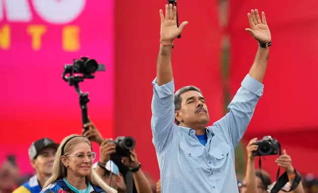 FILE - President Nicolas Maduro, accompanied by first lady Cilia Flores, raises his arms during his closing election campaign rally in Caracas, Venezuela, Thursday, July 25, 2024. Maduro was seeking a third term in the July 28 vote. (AP Photo/Fernando Vergara, File)