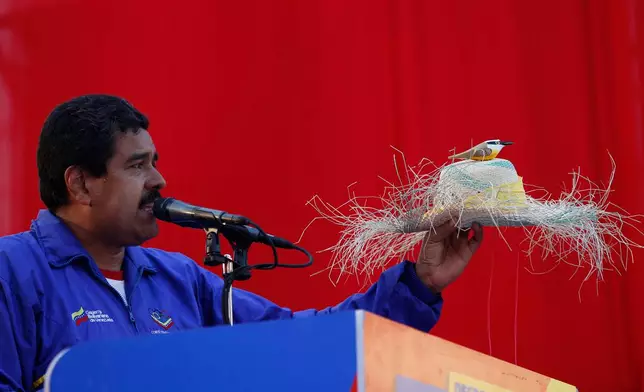 FILE - Venezuela's then acting President Nicolas Maduro holds a farm worker's hat with the figure of a bird perched on the hat's crown during a presidential election campaign rally in Catia La Mar, Venezuela, April 9, 2013. Maduro assured during a campaign rally that the late President Hugo Chavez appeared to him as a "very small bird" to give him his blessing. (AP Photo/Ariana Cubillos, File)