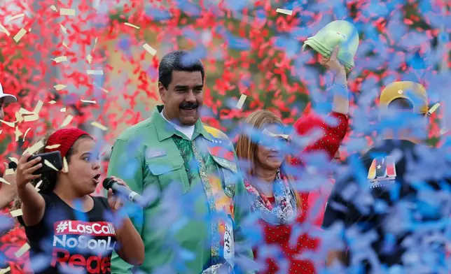 FILE - Venezuela's President Nicolas Maduro stands with his wife, first lady Cilia Flores, right, in a shower of confetti during his closing campaign rally for reelection in Caracas, Venezuela, May 17, 2018. Maduro was seeking a new six-year mandate amid crippling hyperinflation and widespread shortages of food and medicine. (AP Photo/Ariana Cubillos, File)