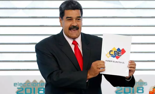 FILE - Venezuela's President Nicolas Maduro holds up the National Electoral Council certificate declaring him the winner of the presidential election, during a ceremony at CNE headquarters in Caracas, Venezuela, May 22, 2018. (AP Photo/Ariana Cubillos, File)
