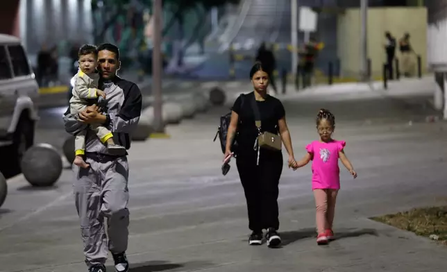 Pedestrians walk past the Miraflores presidential palace after explosions and low-flying aircraft were heard in Caracas, Venezuela, Saturday, Jan. 3, 2026. (AP Photo/Cristian Hernandez)