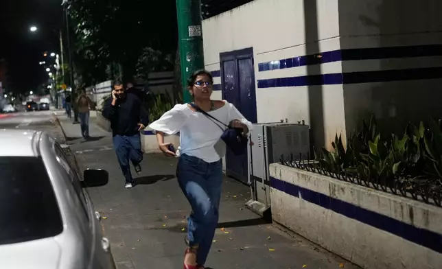 Pedestrians run after explosions and low-flying aircraft were heard in Caracas, Venezuela, Saturday, Jan. 3, 2026. (AP Photo/Matias Delacroix)