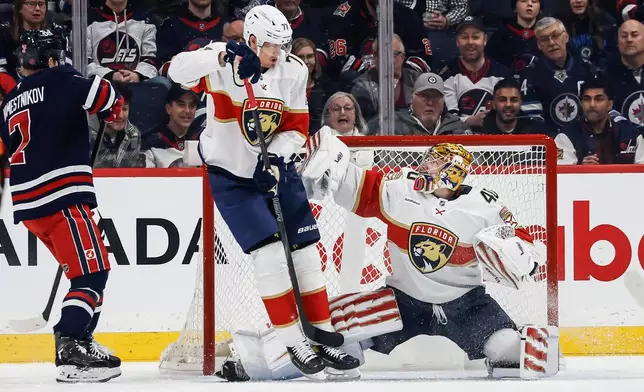 Florida Panthers' Niko Mikkola (77) defends against Winnipeg Jets' Vladislav Namestnikov (7) as goaltender Daniil Tarasov (40) saves the shot during the first period of an NHL hockey game in Winnipeg, Thursday, Jan. 22, 2026. (John Woods/The Canadian Press via AP)
