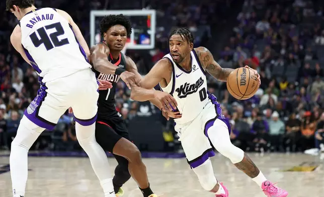 Sacramento Kings guard Malik Monk (0) drives to the basket as center Maxime Raynaud (42) sets a screen on Houston Rockets guard Amen Thompson, center, during the first half of an NBA basketball game, Sunday, Jan. 11, 2026, in Sacramento, Calif. (AP Photo/Sara Nevis)