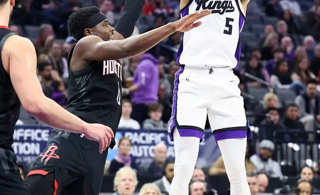 Sacramento Kings guard Nique Clifford (5) shoots over Houston Rockets guard Aaron Holiday, center, during the first half of an NBA basketball game, Sunday, Jan. 11, 2026, in Sacramento, Calif. (AP Photo/Sara Nevis)