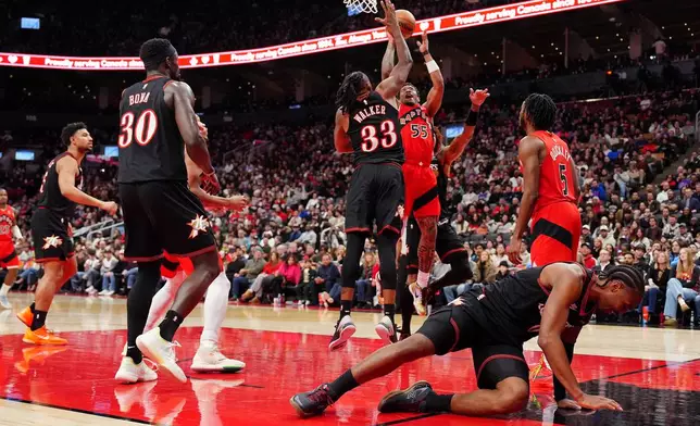Philadelphia 76ers guard Tyrese Maxey, bottom right, rolls on the court as play continues behind him during first-half NBA basketball game action against the Toronto Raptors in Toronto, Sunday, Jan. 11, 2026. (Frank Gunn/The Canadian Press via AP)