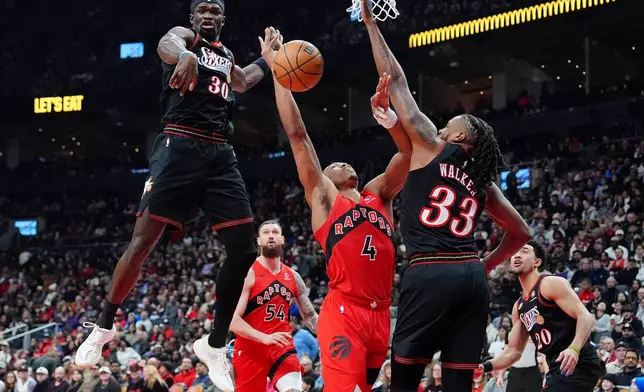 Toronto Raptors forward/guard Scottie Barnes (4) is fouled on his way to the hoop by Philadelphia 76ers forward Jabari Walker (33) as 76ers' Adem Bona (30) looks on during first-half NBA basketball game action in Toronto, Sunday, Jan. 11, 2026. (Frank Gunn/The Canadian Press via AP)