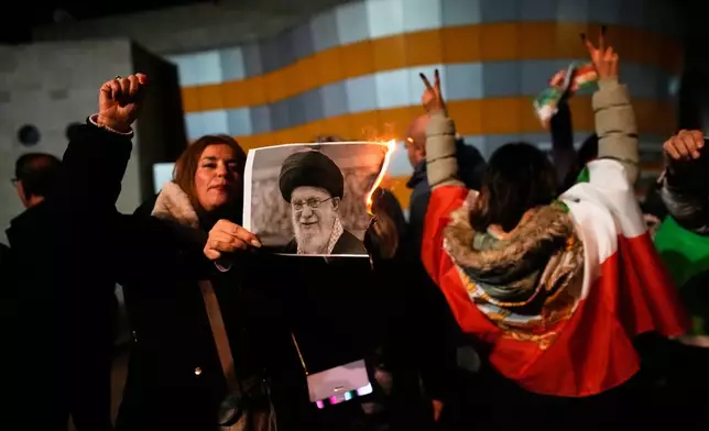 Demonstrators burn a poster depicting Iran's Supreme Leader Ayatollah Ali Khamenei during a rally in support of anti-government protests in Iran, in Holon, Israel Wednesday, Jan. 14, 2026. (AP Photo/Ohad Zwigenberg)