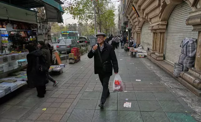 A man walks on a sidewalk in downtown Tehran, Iran, Thursday, Jan. 15, 2026. (AP Photo/Vahid Salemi)
