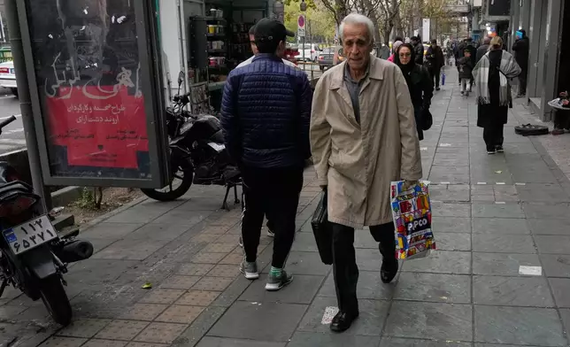 People walk on a sidewalk in downtown Tehran, Iran, Thursday, Jan. 15, 2026. (AP Photo/Vahid Salemi)