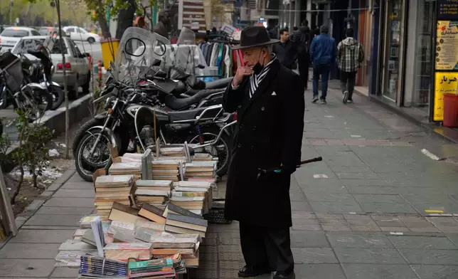 A man looks at books which are placed for sale on a sidewalk in downtown Tehran, Iran, Thursday, Jan. 15, 2026. (AP Photo/Vahid Salemi)