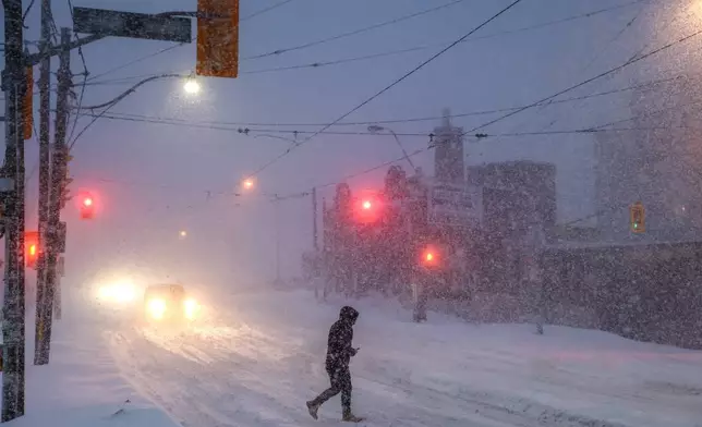 People walk through downtown Toronto as a winter storm moves through the region, Sunday, Jan. 25, 2026. (Cole Burston/The Canadian Press via AP)