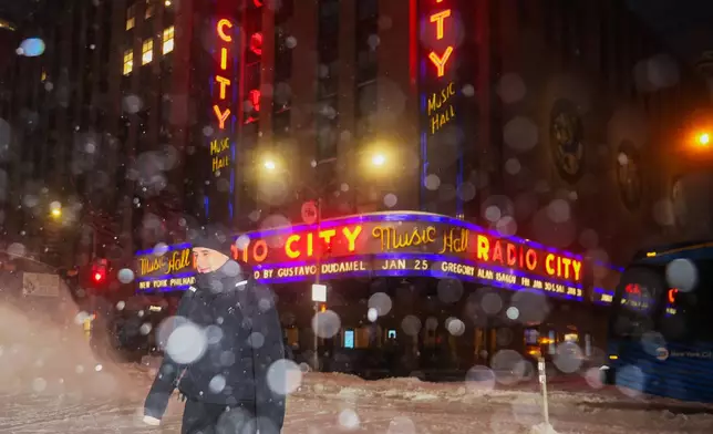 A pedestrian crosses the street near Radio City Music Hall during a winter storm, Sunday, Jan. 25, 2026, in New York. (AP Photo/Heather Khalifa)