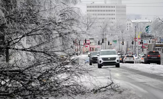 A motorist passes an ice covered tree limb blocking a lane along West End Ave. during a winter storm Sunday, Jan. 25, 2026, in Nashville, Tenn. (AP Photo/George Walker IV)