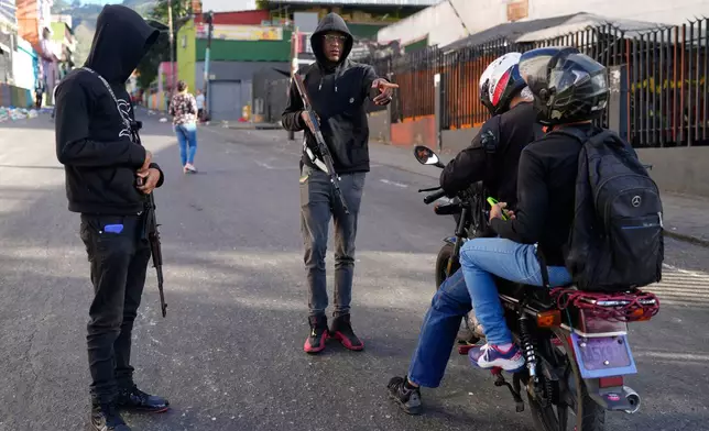 Pro-government armed civilians stop motorcyclists in Caracas, Venezuela, Sunday, Jan. 4, 2026. (AP Photo/Ariana Cubillos)
