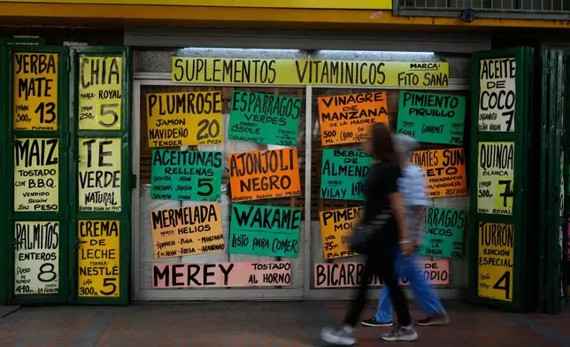 Pedestrians walk past a supermarket in Caracas, Venezuela, Tuesday, Jan. 6, 2026. (AP Photo/Matias Delacroix)