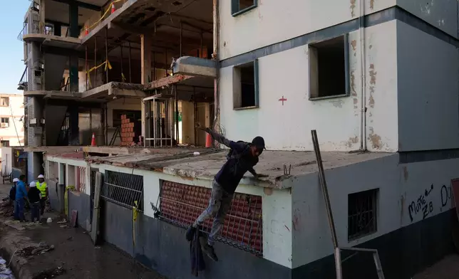 Workers repair damage to an apartment building hit in U.S. strikes during an operation to capture Venezuelan President Nicolas Maduro in La Guaira, Venezuela, Saturday, Jan. 10, 2026. (AP Photo/Ariana Cubillos)
